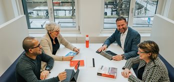 Vier collegas met elkaar in gesprek aan een tafel 